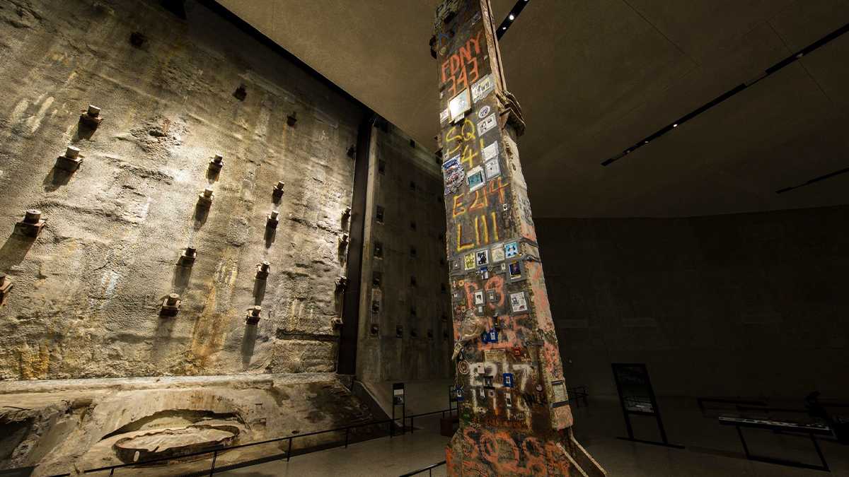 Close up photo of the Last Column with a concrete wall behind it at the National September 11 Memorial & Museum in NYC, New York, USA